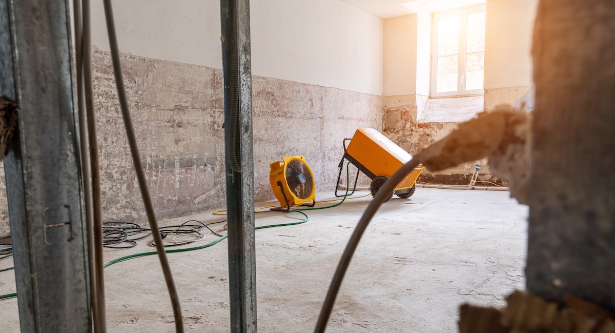 Industrial fans and dehumidifiers removing moisture from a water-damaged apartment building